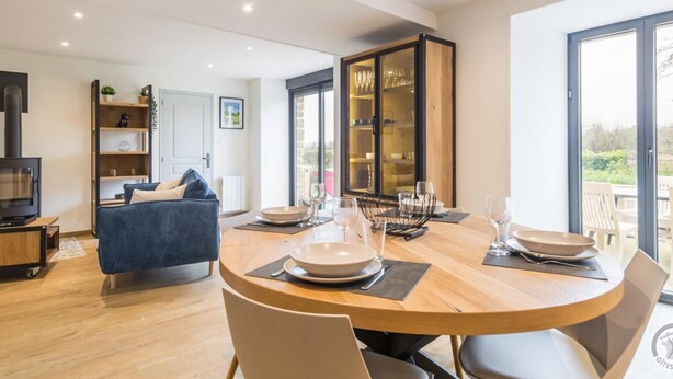 A modern dining area with a round table, chairs, and a glass cabinet in the background.