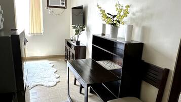 A compact living space with a dark wooden desk, a chair, a television, and a small potted plant.