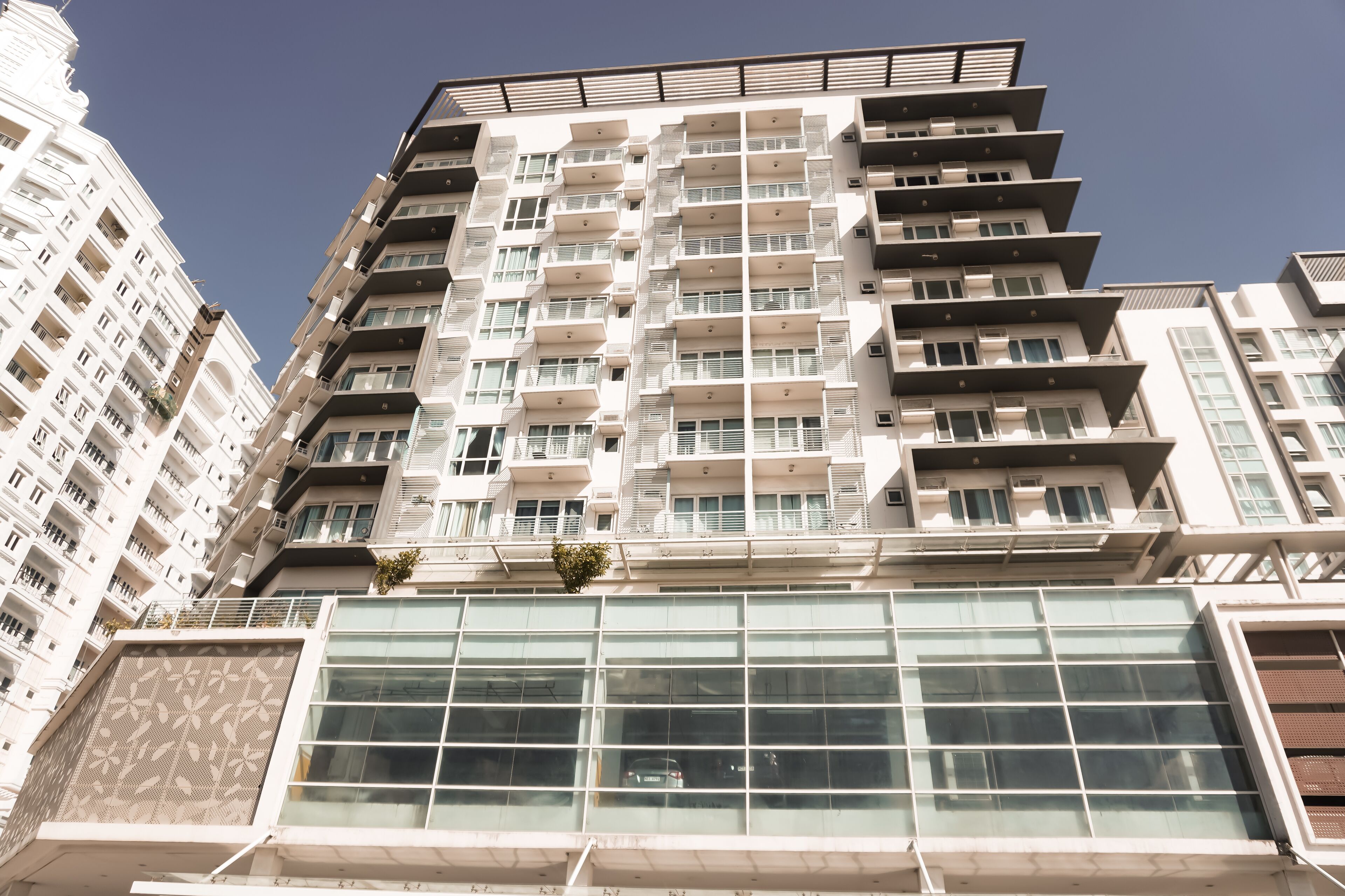 Un immeuble moderne à plusieurs étages, doté de balcons, de grandes fenêtres et d’une façade en verre.