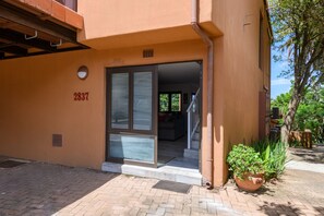 Ein Gebäudeeingang mit Glastür, einem Blumentopf und der Hausnummer 2837 an der Wand.
