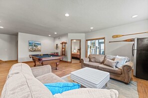Ein Wohnzimmer mit Billardtisch, einer Couch, einem Couchtisch und einem Kühlschrank.