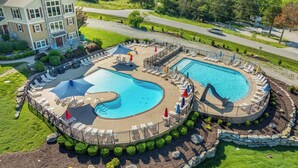 Uma grande piscina ao ar livre com design circular, rodeada por espreguiçadeiras e guarda-sóis.