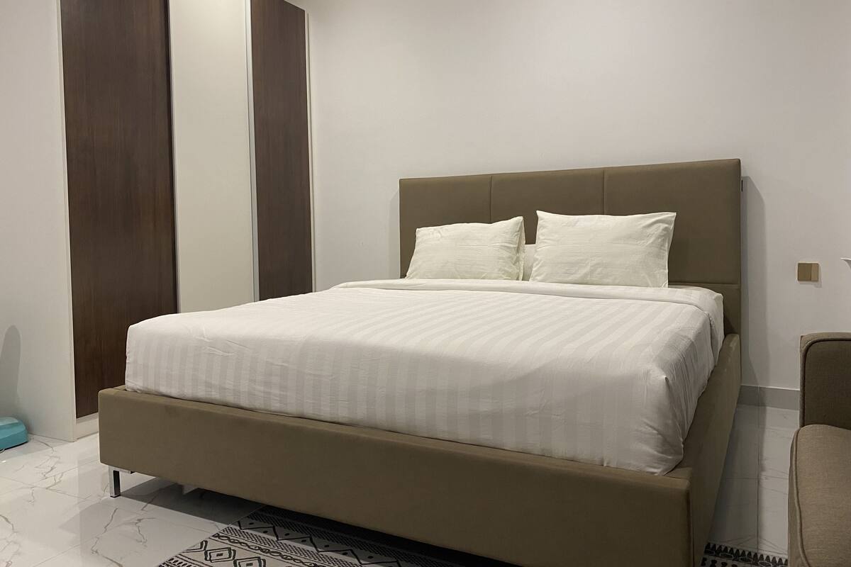 Ein modernes Schlafzimmer mit einem großen Bett, einer Kopfteil und einem Holzschrank.