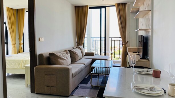 Een moderne woonkamer met een bank, een eettafel gedekt met borden en bestek, en een televisie op een houten plank.