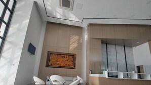 Een moderne lobby met een receptiebalie, een zithoek en een groot kunstwerk aan de muur.