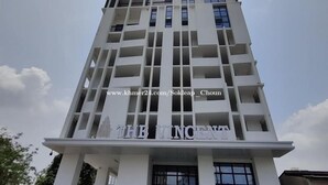 Een hoog, modern gebouw met een opvallende ingang en meerdere balkons.