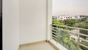Un balcón con barandilla de metal, vistas a edificios y cielo despejado.