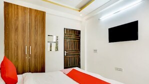 Una habitación de hotel con una cama, un televisor montado en la pared y un armario.