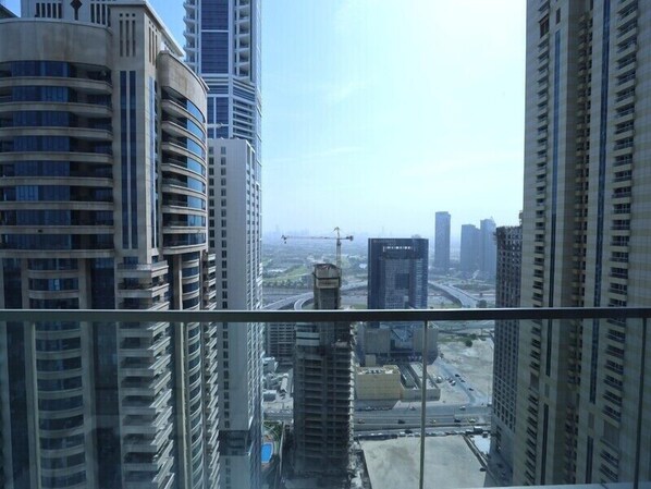 A high-rise building with multiple floors and a view of a cityscape in the background. - Charming 1BR Ocean Heights (Dubai)
