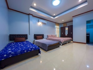 Una habitación de hotel con tres camas, una lámpara en el techo, un aire acondicionado y un armario.
