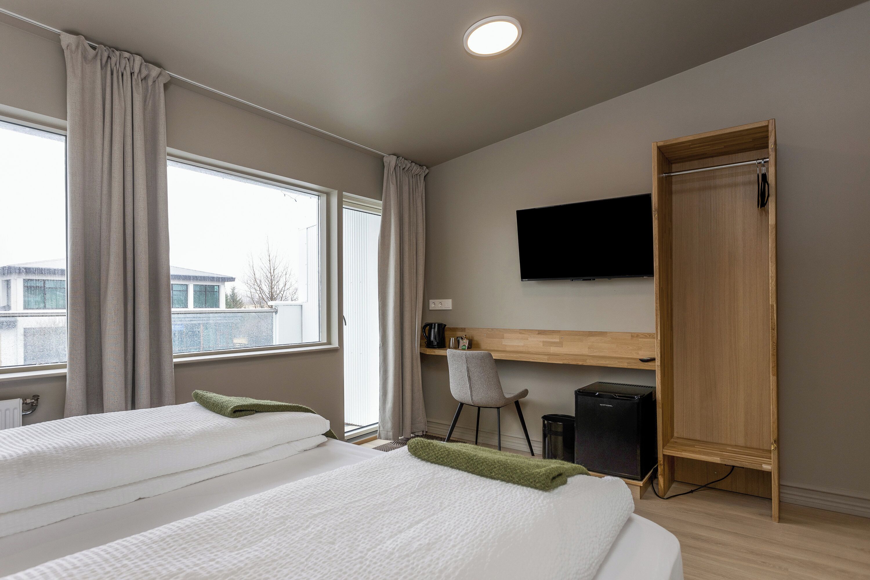 Une chambre d’hôtel avec deux lits, un bureau, une chaise, une télévision et une armoire.
