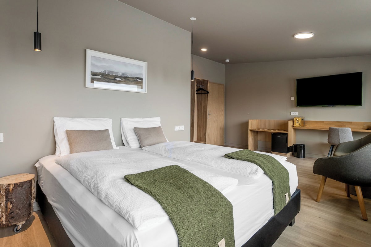 Una habitación de hotel moderna con una cama grande, un escritorio y un televisor.