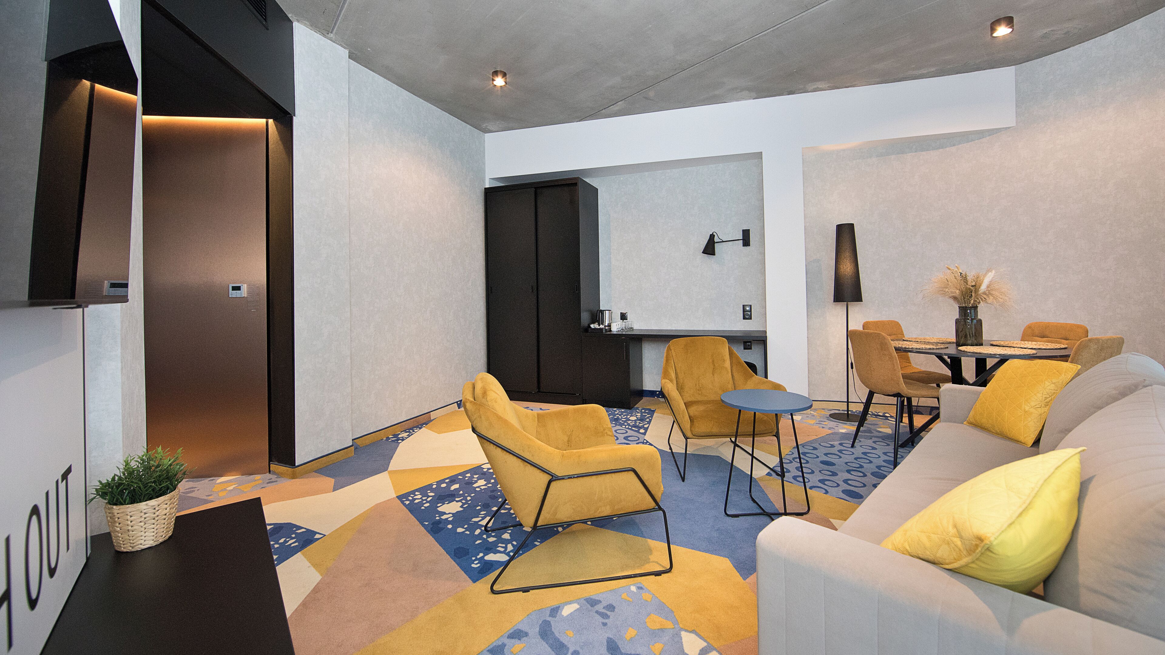 A modern living room with a sofa, armchairs, a coffee table, and a dining area with a table and chairs.