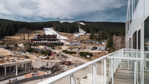 Un sitio de construcción con un edificio en desarrollo, rodeado de un área boscosa y una pista de esquí.