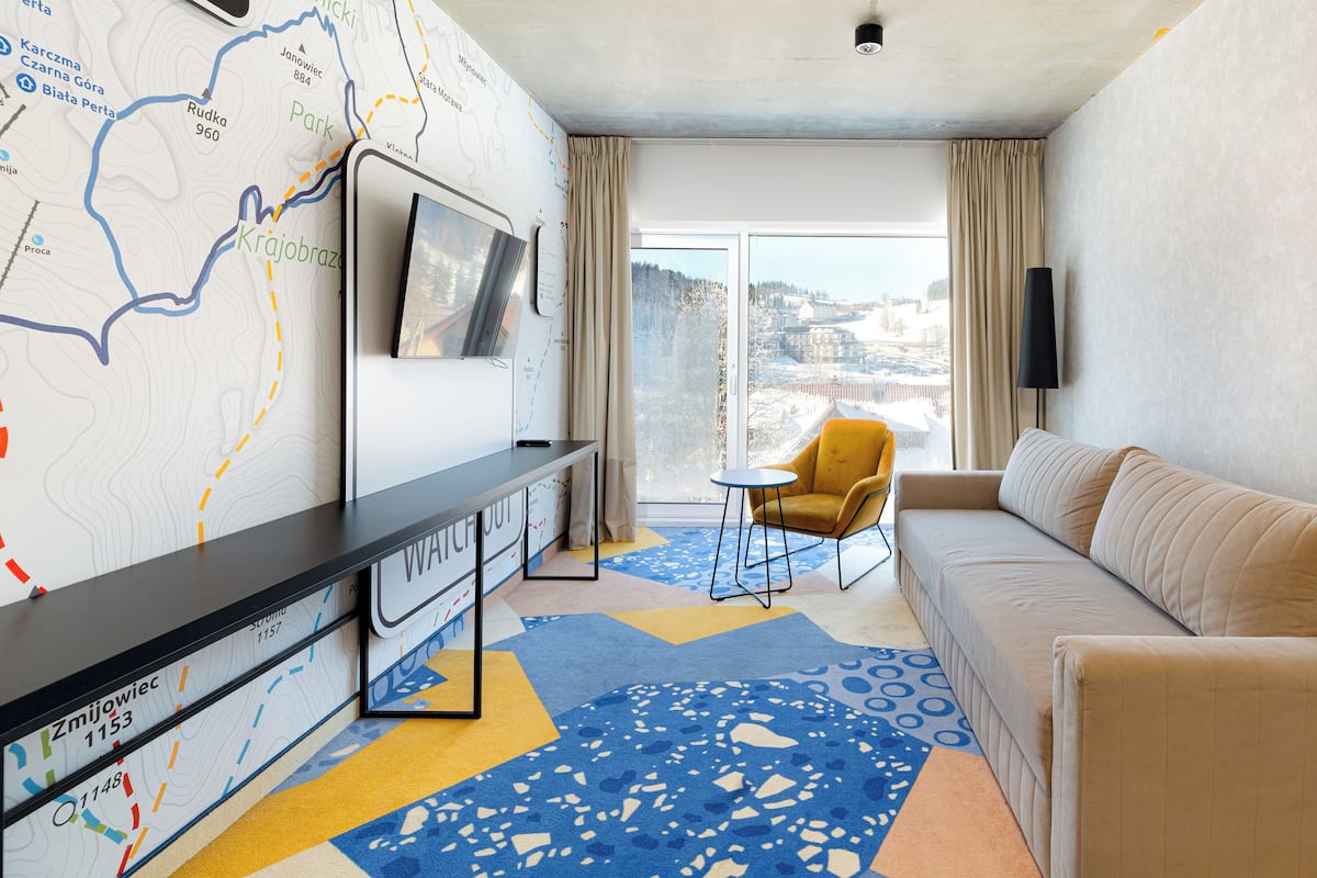 Une chambre d’hôtel avec une grande carte accrochée au mur, un canapé, un fauteuil et une petite table.