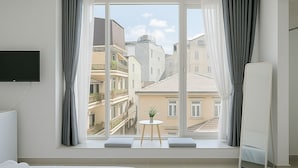 A modern hotel room with a large window, a bed, a small table with a plant, and a TV mounted on the wall. - Lam Anh Hotel (Xuan Huong - Da Lat)