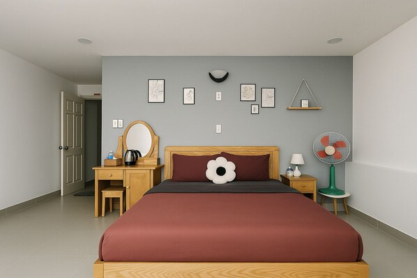 A bedroom with a large bed, a wooden dresser, a mirror, a bedside table with a lamp, a wall-mounted shelf, and a floor fan. - Lam Anh Hotel (Xuan Huong - Da Lat)