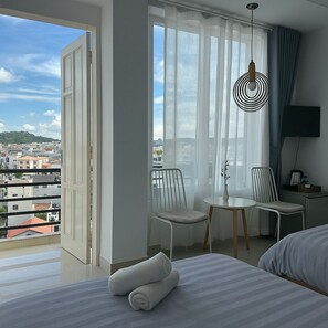 A hotel room with a balcony, a bed, two chairs, a small table, and a TV. - Lam Anh Hotel (Xuan Huong - Da Lat)