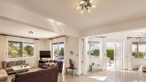 A spacious living room with a sofa, TV, and a dining area.