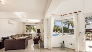 A spacious living room with a large window, a sofa, a coffee table, and a small side table.