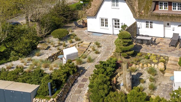 A white house with a thatched roof, stone pathway, and outdoor seating area. - Gaat 7 - Wohnen im Historischen Ortskern Keitum (Sylt / OT Keitum)