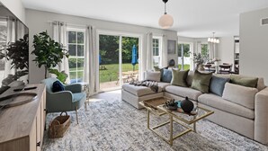 A spacious living room with a sofa, armchair, and coffee table, large windows, and a view of the outdoors. - Last Minute Deal ! New Construction 3 blocks to Boone St. and walkable to ocean wall (Narragansett)