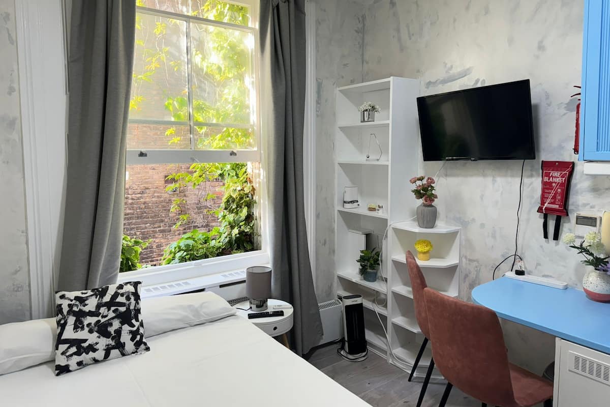 A bedroom with a bed, a desk, a chair, a TV, and a bookshelf.