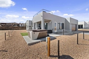 A modern building with a flat roof, a staircase, and a small outdoor seating area. - Stargazer 4BR Desert Retreat | Hot Tub & Deck (Page)