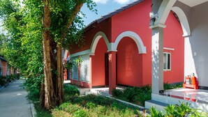 A red building with white arches, a fire extinguisher, and a tree in the foreground. - Phuc Thang Resort  (Phu Quoc)