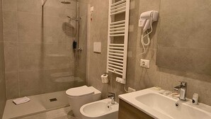 A modern bathroom with a bathtub, two sinks, a shower, and a towel rack. - Hotel Domus Rome (Rome)