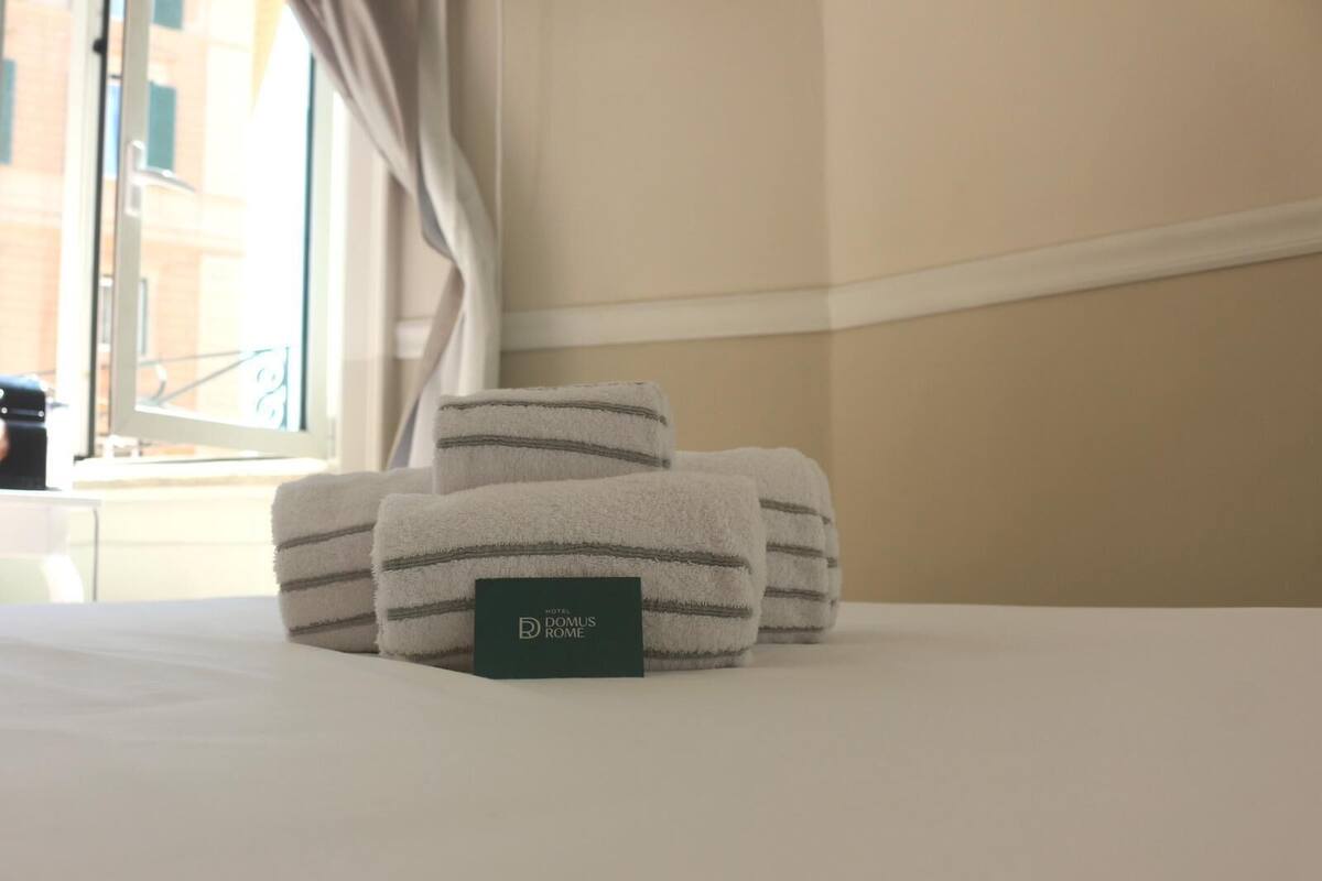 A neatly made bed with folded towels and a hotel room sign.