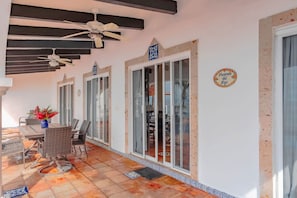 A covered outdoor area with a table and chairs, a ceiling fan, and a sign indicating a restaurant.