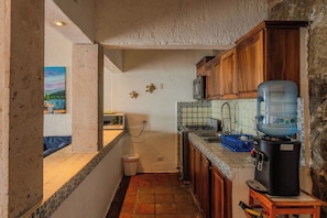 Una cocina funcional con dispensador de agua, microondas y lavamanos.