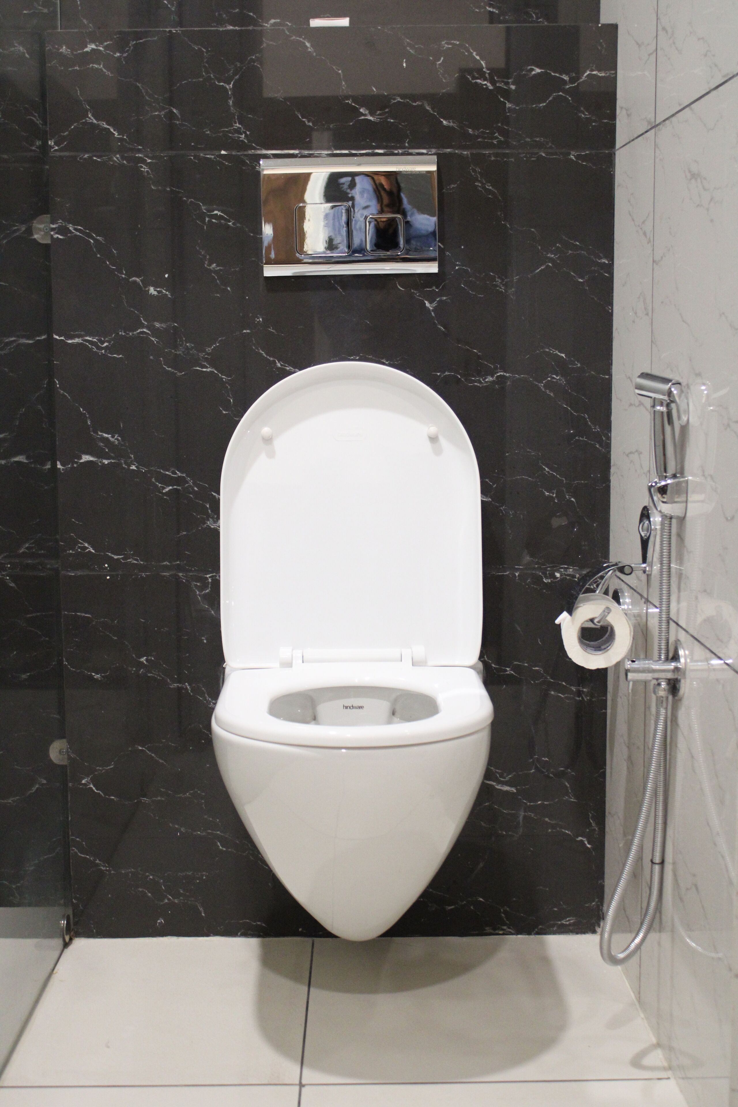 A modern bathroom with a white toilet, black marble walls, and a shower.