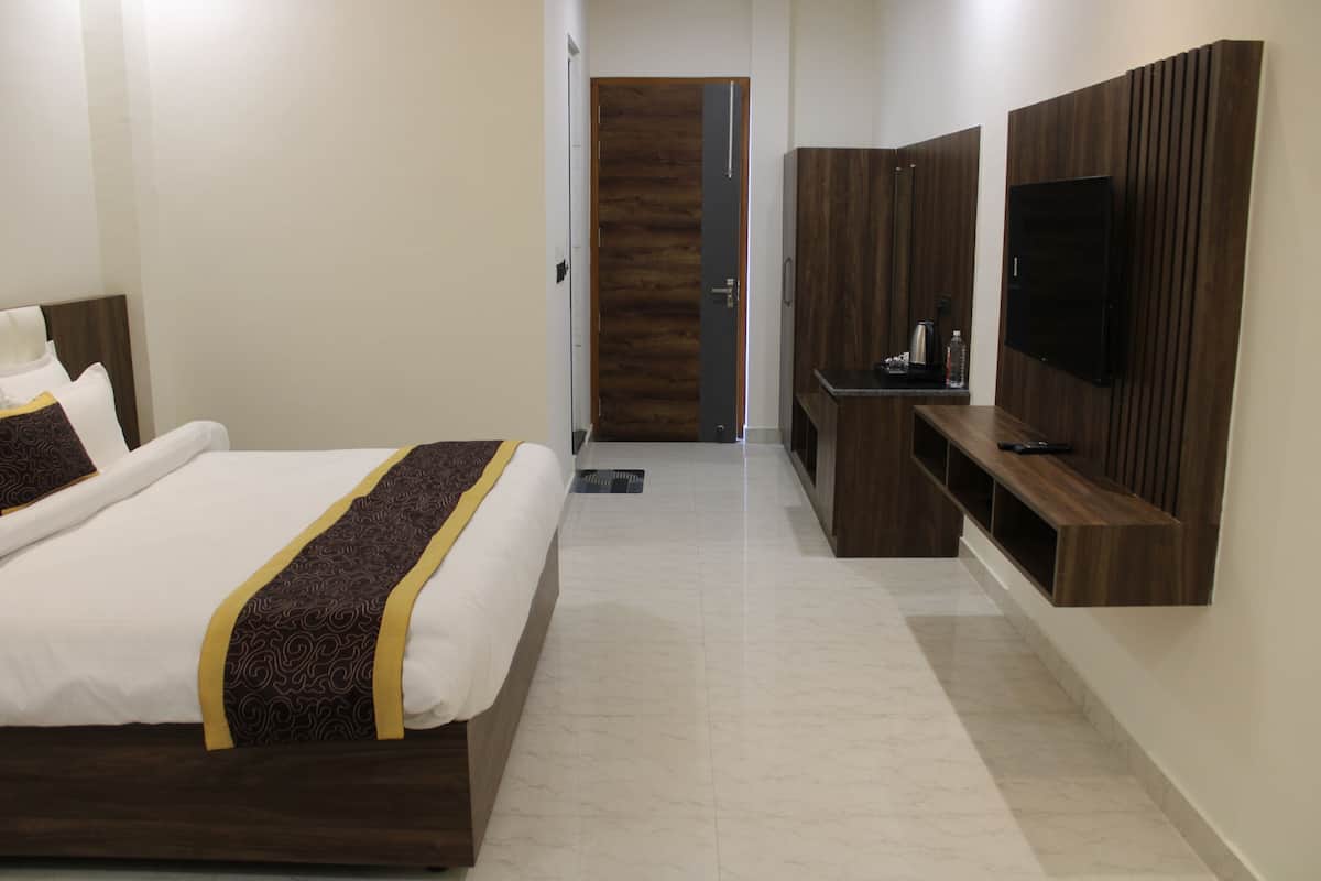 Ein Hotelzimmer mit einem Bett, einem an der Wand befestigten Fernseher und einem Holzschrank.