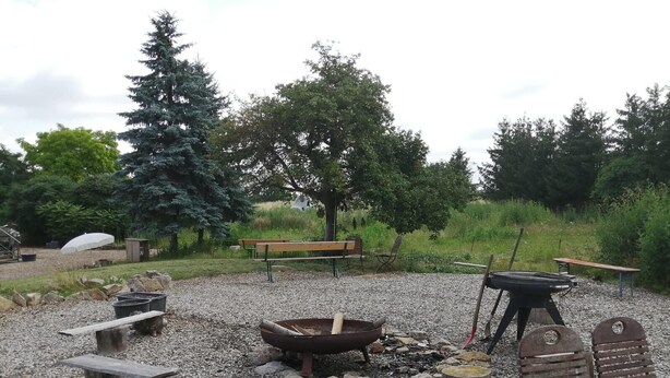 An outdoor seating area with a fire pit, benches, and a grill.