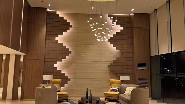 A modern lobby with a central seating area, wooden panel walls, and a unique ceiling design. - Comfy Studio UnitL OneMadison35 (Iloilo)