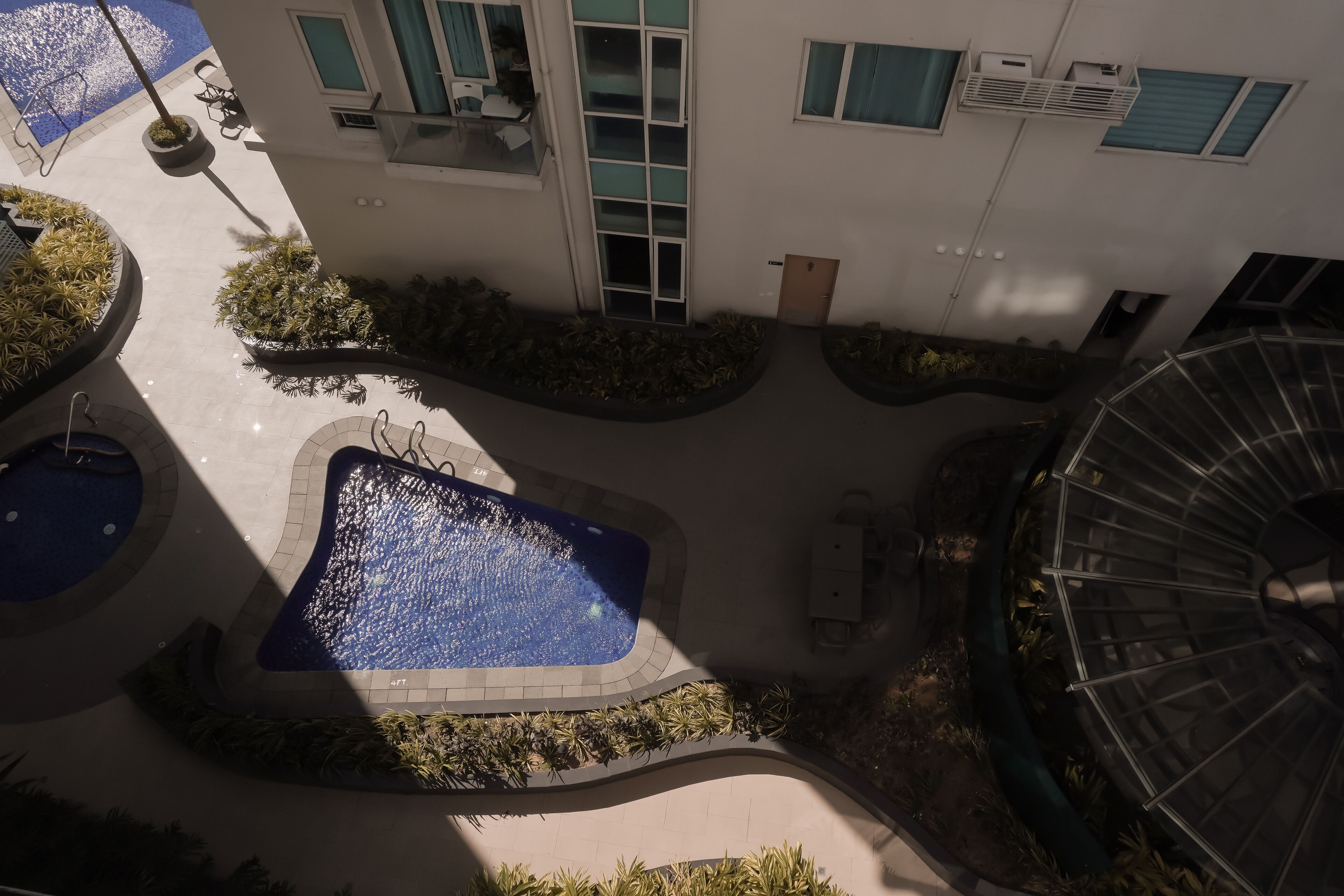 A courtyard with a central pool, surrounded by planters and a spiral staircase.