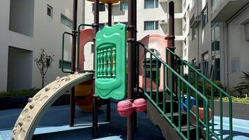 A playground with a slide, climbing structures, and a red flower decoration.