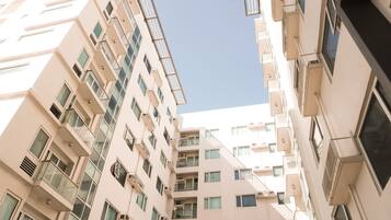 A multi-story residential building with balconies, large windows, and a clear sky.