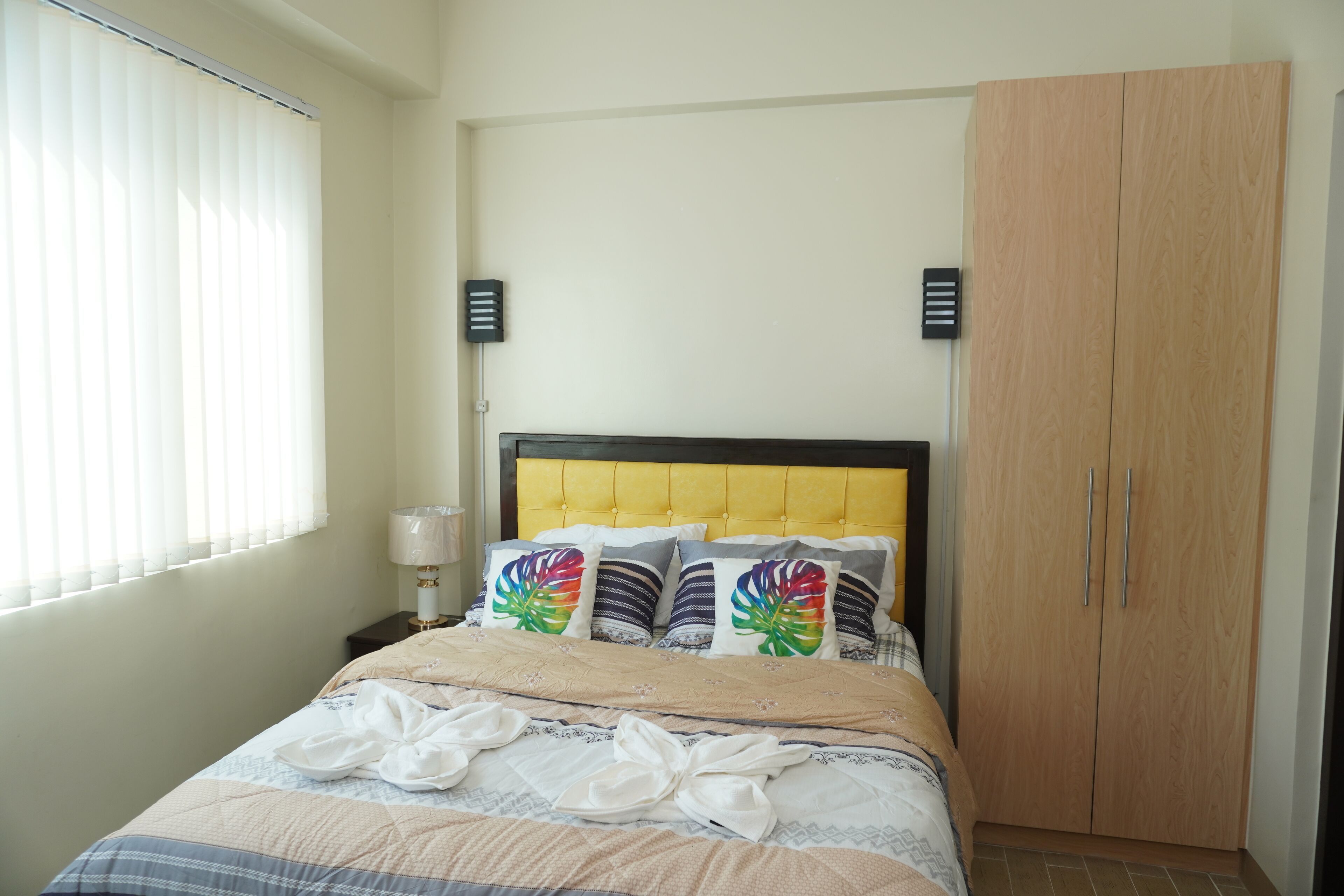 A bedroom with a bed, a nightstand, a lamp, and a wardrobe.