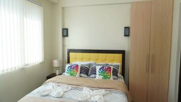 A bedroom with a bed, a nightstand, a lamp, and a wardrobe.
