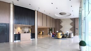 A spacious lobby with a reception desk, seating areas, and a large potted plant. - Comfy Studio UnitL OneMadison35 (Iloilo)
