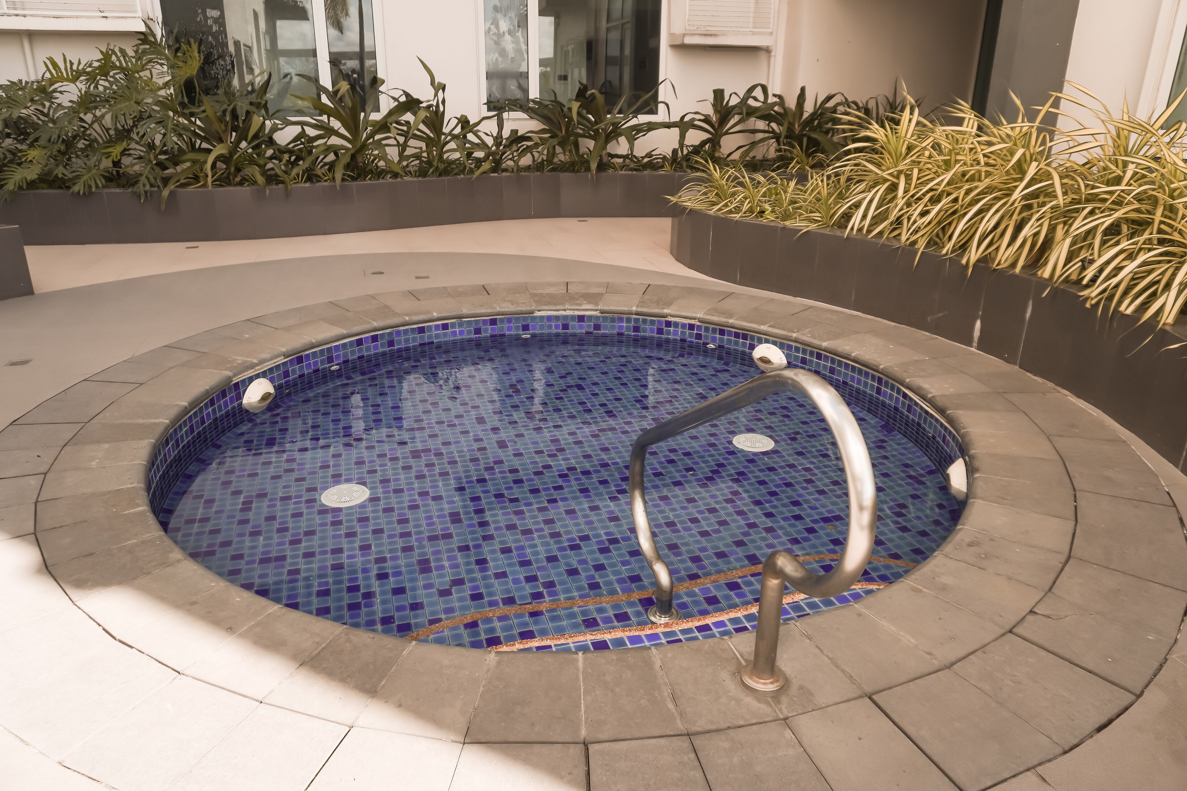 Una piscina circular con mosaicos azules y una barandilla de metal.