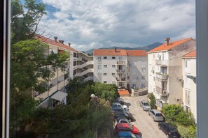 Et boligområde med etagebyggeri, en parkeringsplads og et bjergtag i baggrunden.