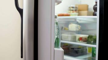 Een koelkast met waterdispenser en planken vol met verschillende soorten eten.