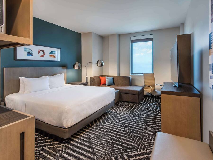 Una habitación de hotel moderna con una cama grande, un sofá, un escritorio y una televisión.