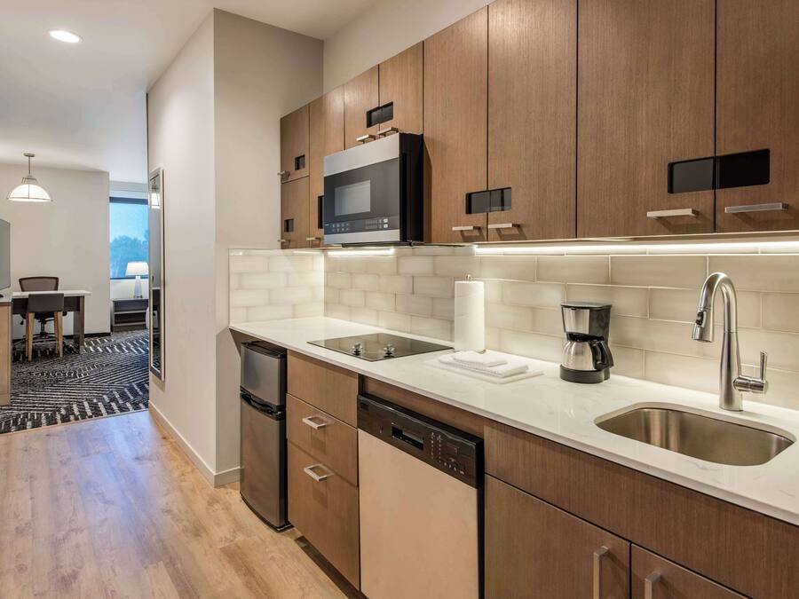 A modern kitchen with wooden cabinets, a stainless steel sink, a microwave, and a dishwasher.