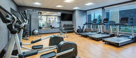 Un gimnasio con cintas de correr, elípticas y máquinas de pesas.