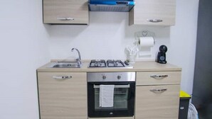 A compact kitchen with a gas stove, oven, and a small sink. - 2 Bedroom Apartment in Cutrofiano (Cutrofiano)
